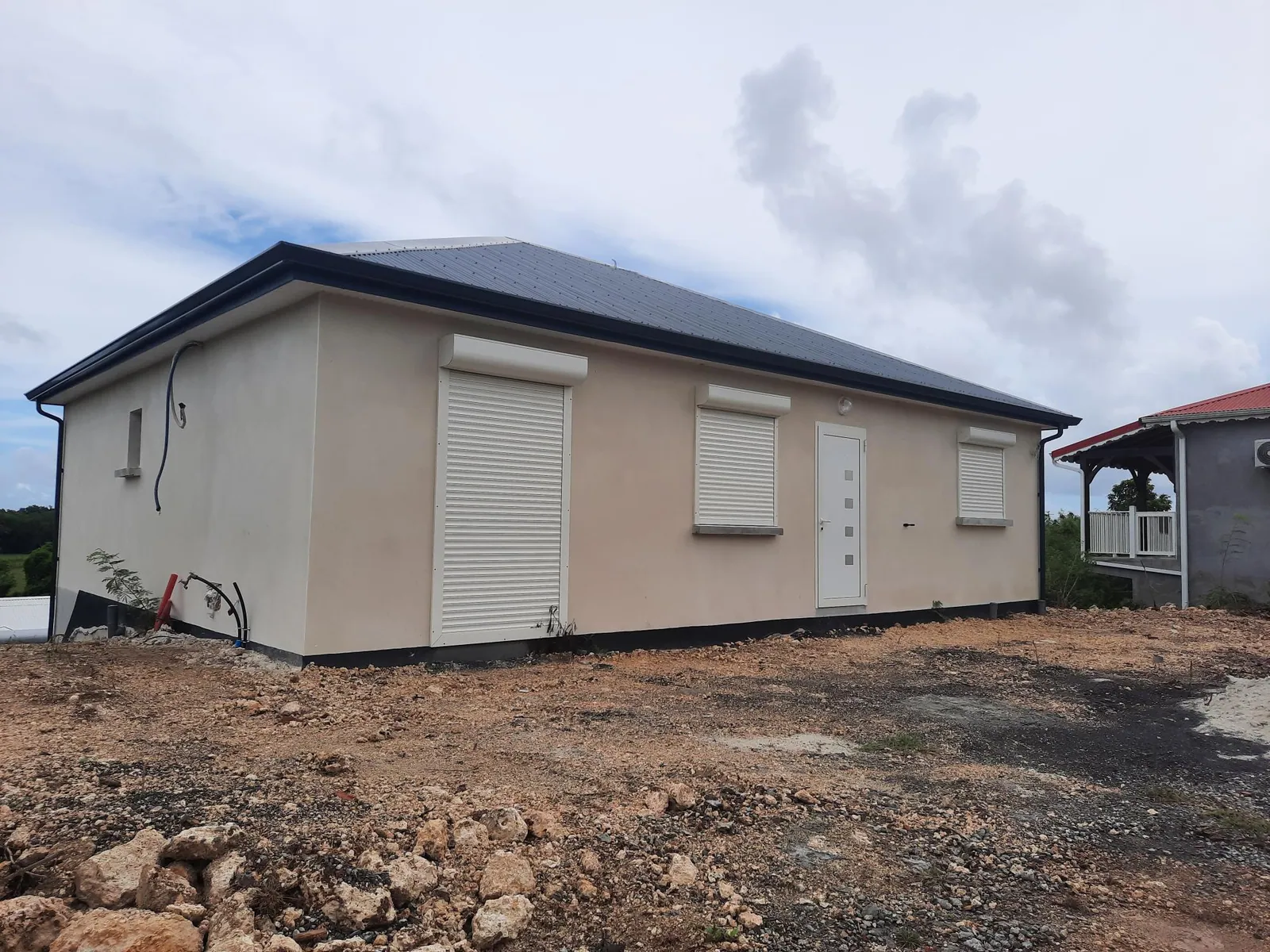 Maison individuelle beige de plain-pied construite par GLG, volets roulants et toiture sombre