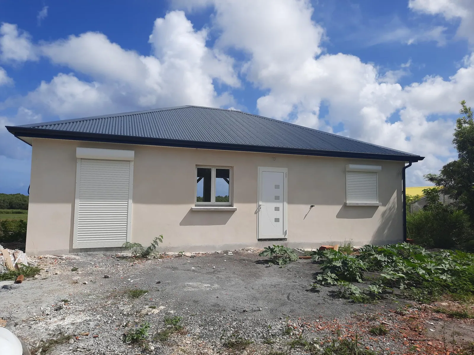 Maison individuelle claire construite par GLG en Guadeloupe, toiture métallique sombre